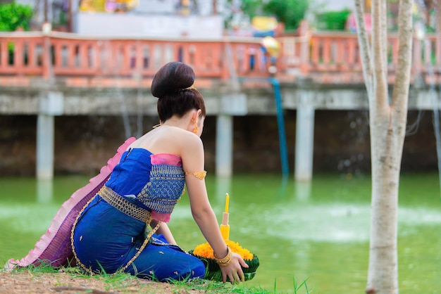 Portrait of beautiful asian woman in Thai dress traditional praying hold kratong for join loy kratong festival at thailand