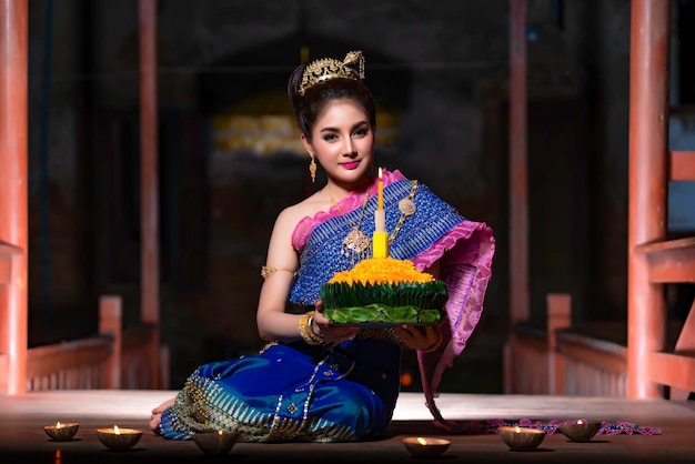 Portrait of beautiful asian woman in Thai dress traditional praying hold kratong for join loy kratong festival at thailand