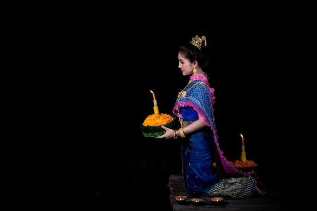 Portrait of beautiful asian woman in Thai dress traditional praying hold kratong for join loy kratong festival at thailand