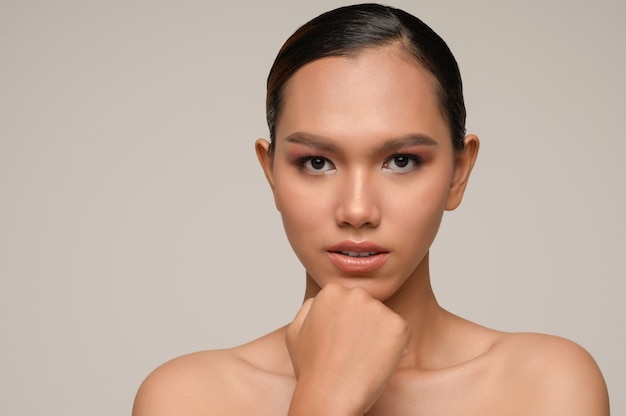 Portrait of beautiful asian woman touches chin with beautiful natural clean skin