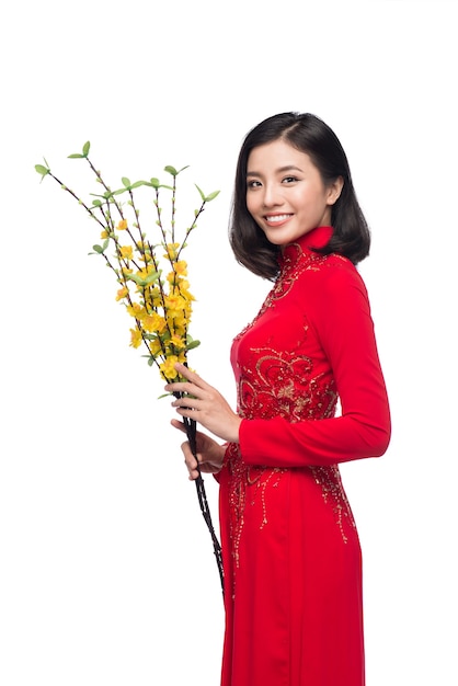 Portrait of a beautiful Asian woman on traditional festival costume Ao Dai holding Hoa Mai tree (Ochna Integerrima) flower. Tet holiday. Lunar New Year.