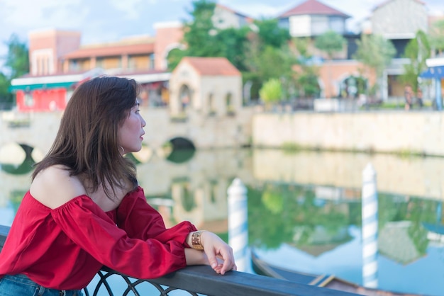 Портрет красивой азиатской женщины в городе Тоскана. Люди Таиланда позируют для фото, чтобы увидеть мост и реку.