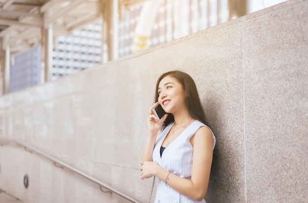 도심에서 휴대전화를 사용하는 아름다운 아시아 여성의 초상화