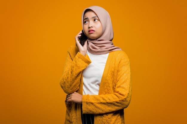 友人と話し、退屈を感じる携帯電話を使用して美しいアジアの女性の肖像画