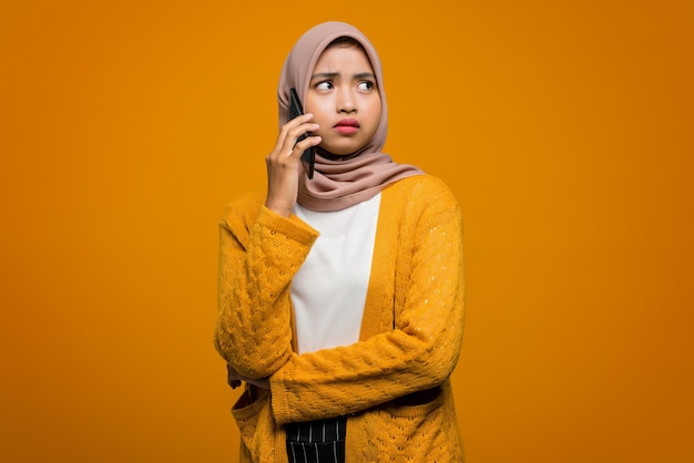 友人と話し、退屈を感じる携帯電話を使用して美しいアジアの女性の肖像画