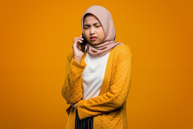 友人と話し、退屈を感じる携帯電話を使用して美しいアジアの女性の肖像画