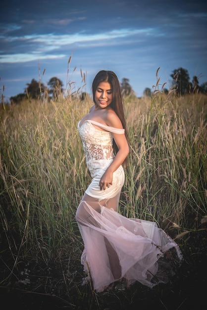 Portrait of beautiful asian woman wear white dress in the field on sunsetThailand people