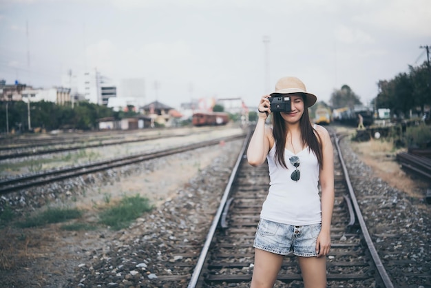 鉄道のビンテージスタイルでカメラを手に白いTシャツの美しいアジアの女性の肖像画