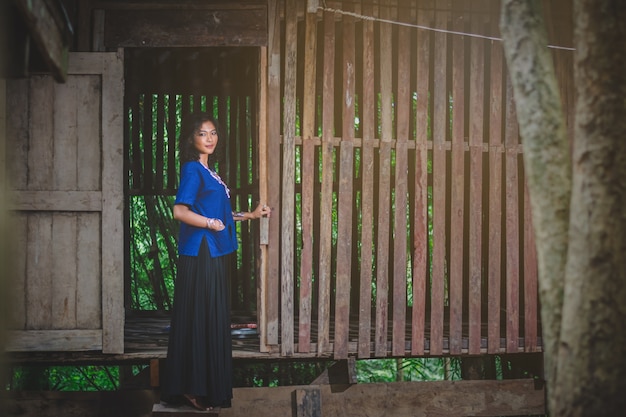 Portrait of beautiful Asian woman with local dress, standing at the country house’ door 