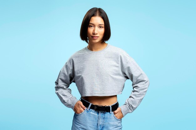 Foto ritratto di una bella donna asiatica con i capelli bob eleganti che indossa abiti casuali guardando la telecamera che posa isolata su uno sfondo blu concept di modello di moda