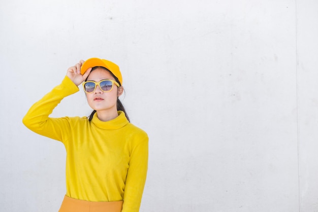 Portrait of beautiful asian woman in yellow cloths on dirty white wallHipsters girl wear yellow hat take a pictureThailand people