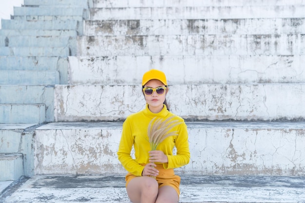 Portrait of beautiful asian woman in yellow clothshipsters girl\
wear yellow hat on stair for take a picturethailand people in\
yellow tone style