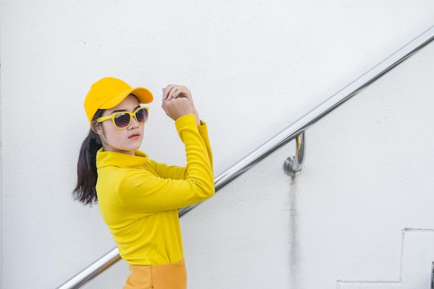 Portrait of beautiful asian woman in yellow clothshipsters girl\
wear yellow hat on stair for take a picturethailand people in\
yellow tone style