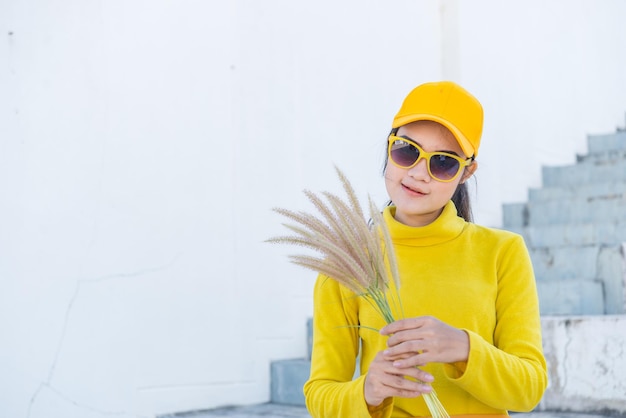 Portrait of beautiful asian woman in yellow clothshipsters girl\
wear yellow hat on stair for take a picturethailand people in\
yellow tone style