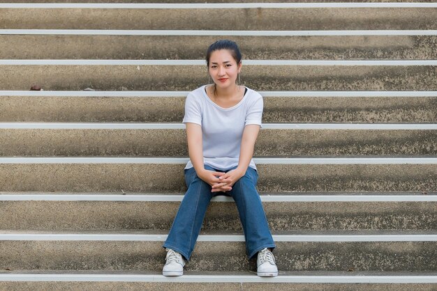 美しいアジアの女性の肖像画屋外で写真を撮るためのヒップスターの女の子タイの人々は階段に立っています