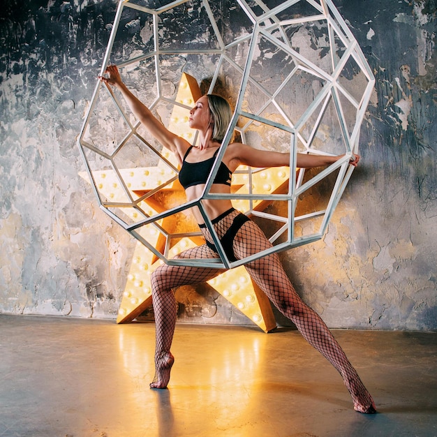 portrait of beautiful attractive blonde woman dancer with huge star on the background  in the loft