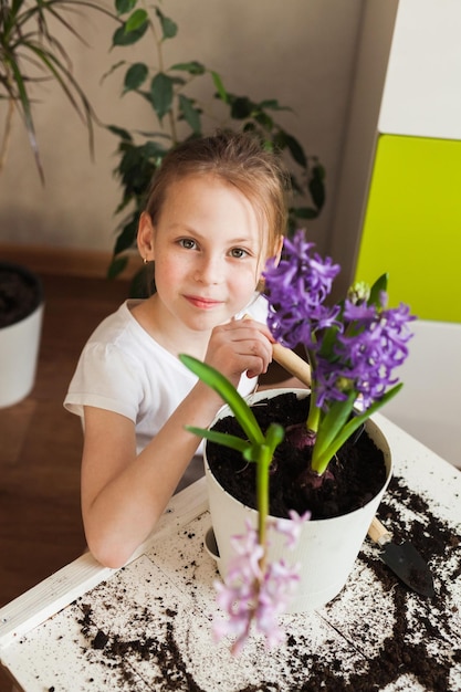 Photo portrait of a beautiful baby girl at home gardening replanting blooming spring flowers