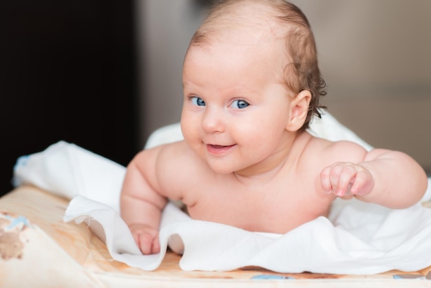 Portrait of a beautiful baby girl lies on a white sheet in her room