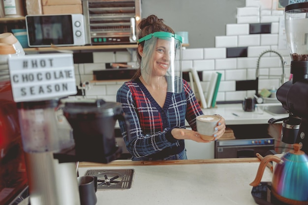 Portrait of beautiful barista girl holding cup of coffee