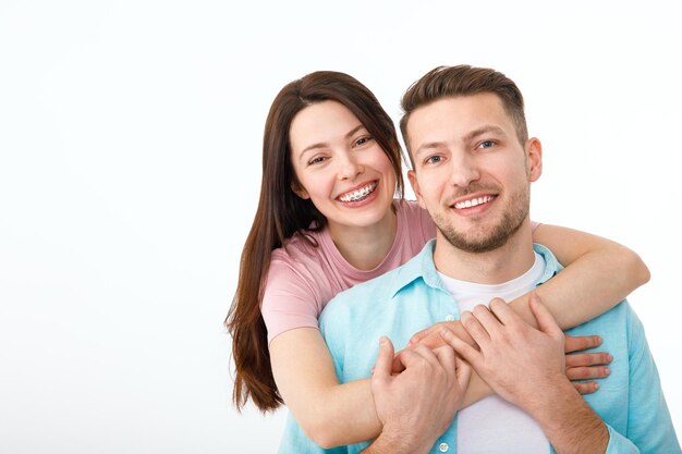 Portrait of a beautiful beloved couple A guy and a girl hug each other and look at the camera smiling On a white background