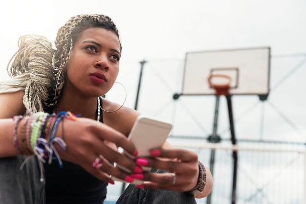 Portrait of beautiful black woman using her mobile in her neighborhood. Slum Concept.