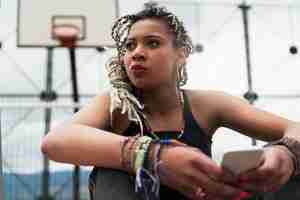 Photo portrait of beautiful black woman using her mobile in her neighborhood. slum concept.