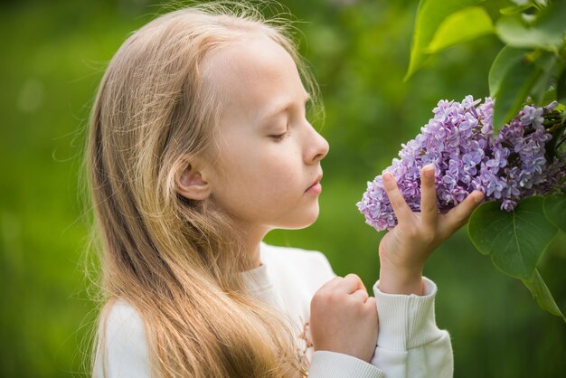 Portrait of a beautiful blond girl with a purple lilac in her hands