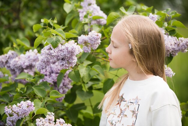 Portrait of a beautiful blond girl with a purple lilac in her hands