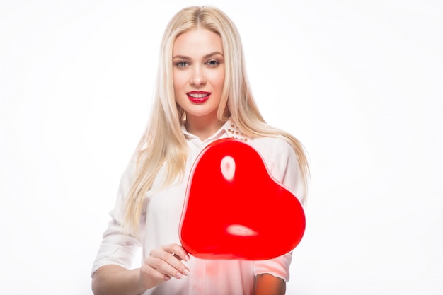 Photo portrait of beautiful blond woman with bright makeup and red heart in hand