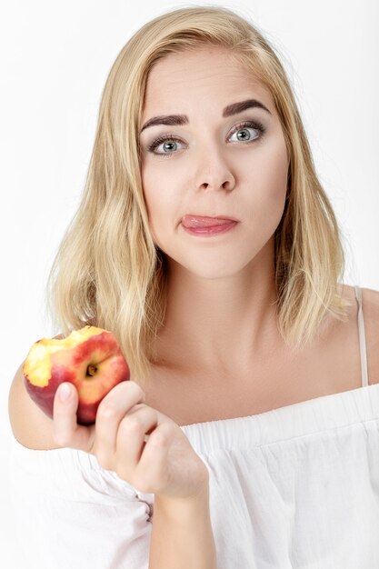 Portrait of beautiful blond woman with pleasure eating nectarine