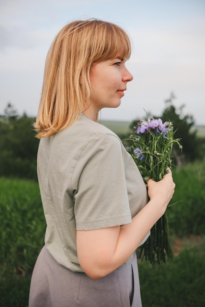 portrait of a beautiful blonde girl in a field with a bouquet of flowers