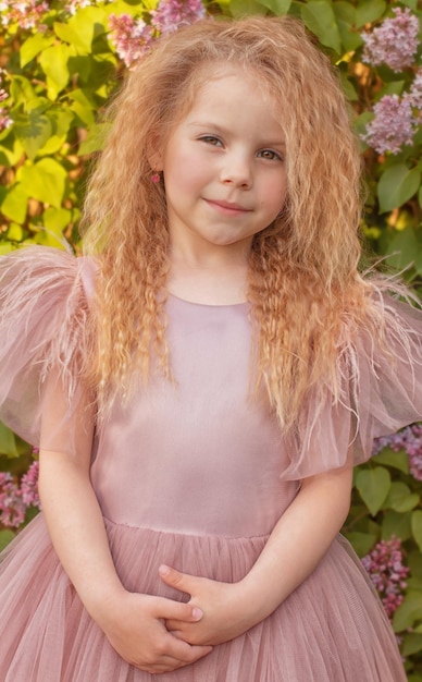 Portrait of a beautiful blonde girl in a pink dress with long hair