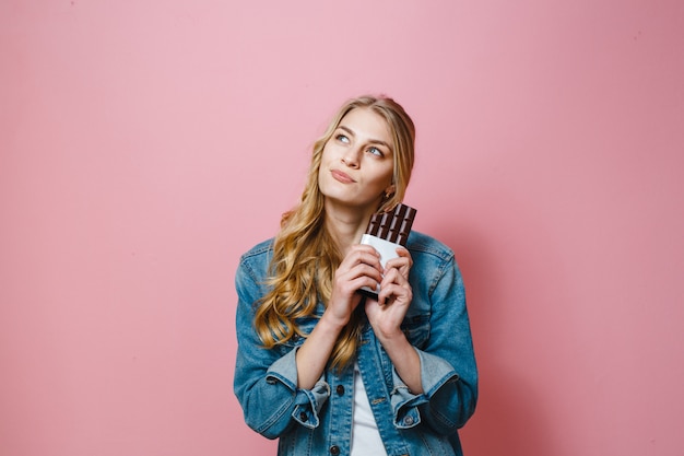 Un ritratto di una bella donna bionda che mangia cioccolato è eccitato