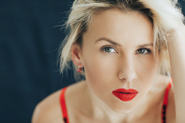 Portrait of a beautiful blonde woman in a red lipstick on her lips