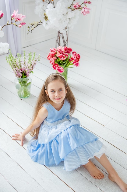 Portrait of a beautiful blueeyed girl little among spring flowers Mothers Day Womens Day Easter