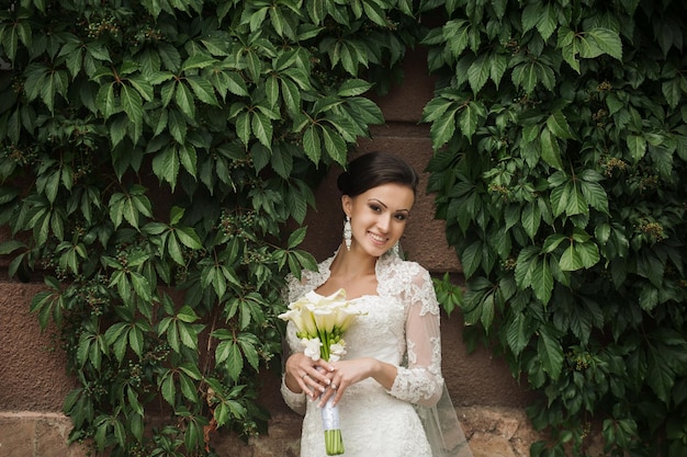 屋外の美しい花嫁の肖像画ユリの花束と若い笑顔の花嫁
