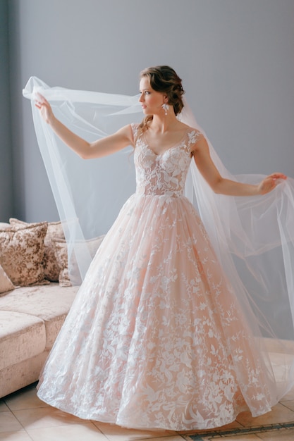 Portrait of beautiful bride in white vintage dress with veil posing with hands apart