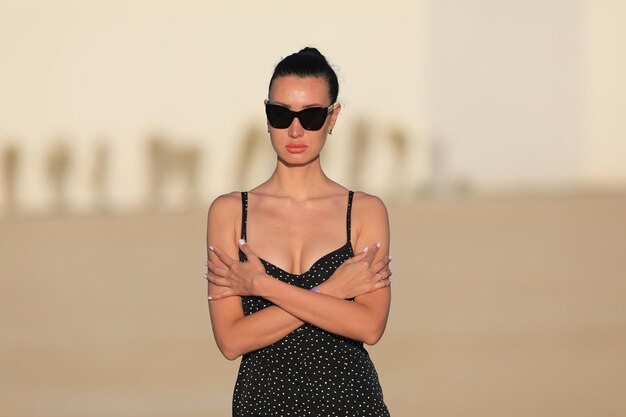 portrait of a beautiful brunette girl in sunglasses in a black dress in summer