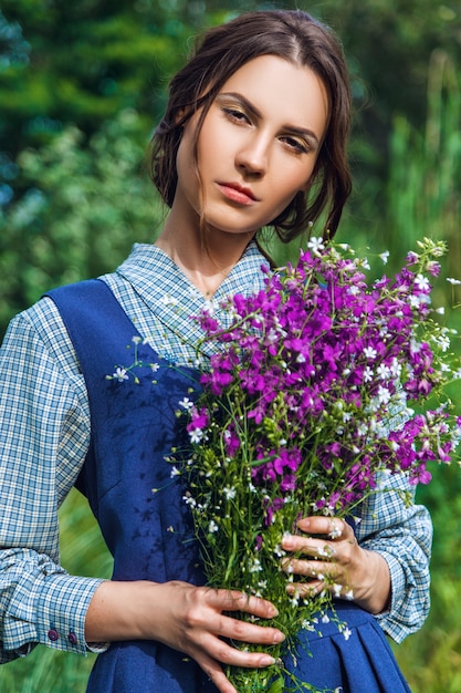Портрет красивой брюнетки в синем платье в поле