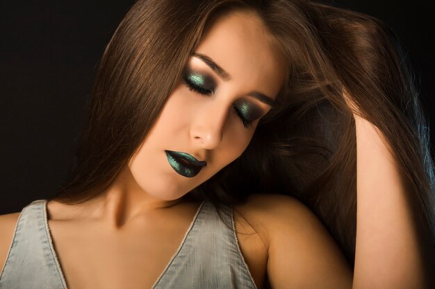 Photo portrait of beautiful brunette woman with high fashion bright makeup over a black background