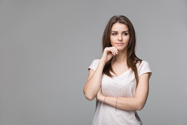 Ritratto di bella donna castana con trucco naturale su sfondo grigio