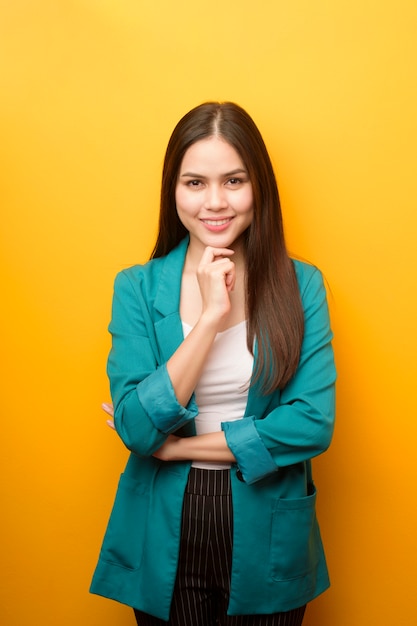 Portrait of beautiful business woman in green suit on yellow background
