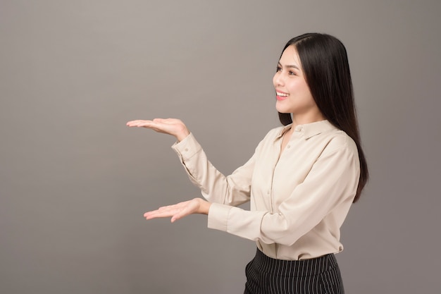 Portrait of Beautiful business woman is showing something on gray wall