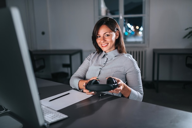 Portrait of beautiful businesswoman with headset working at night.