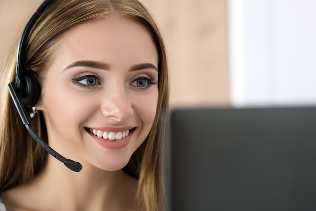 Portrait of beautiful call center operator at work. Woman with headset talking to someone online