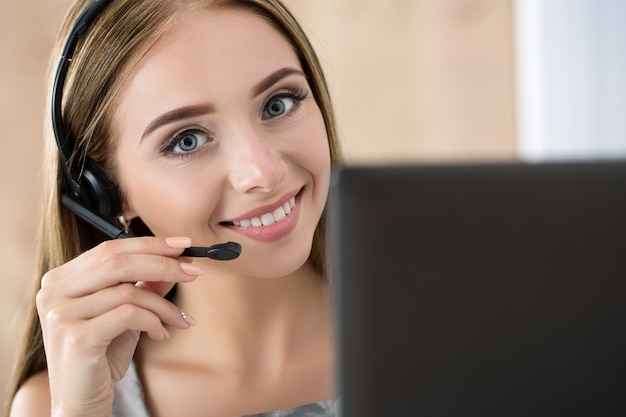 Portrait of beautiful call center operator at work. Woman with headset talking to someone online