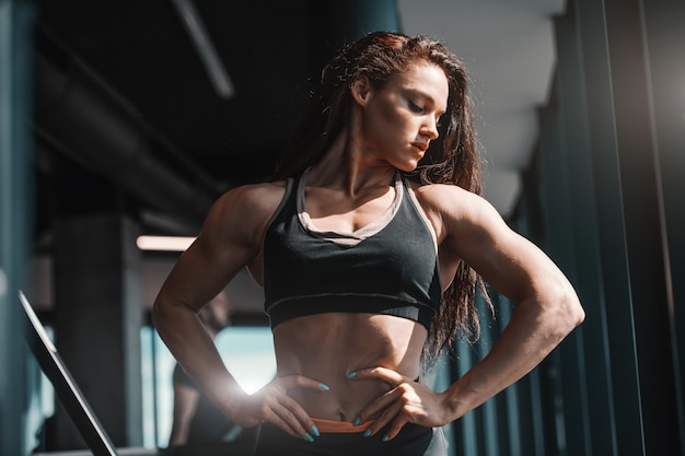 Portrait of beautiful Caucasian female bodybuilder posing with hands on hips in gym. You are the creator of your own destiny.