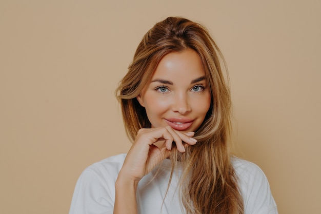 Ritratto di bella donna caucasica in maglietta bianca che guarda con un bel sorriso la telecamera