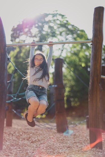 Photo portrait of a beautiful caucasian girl is doing push-ups on the horizontal bar in the the playgroun