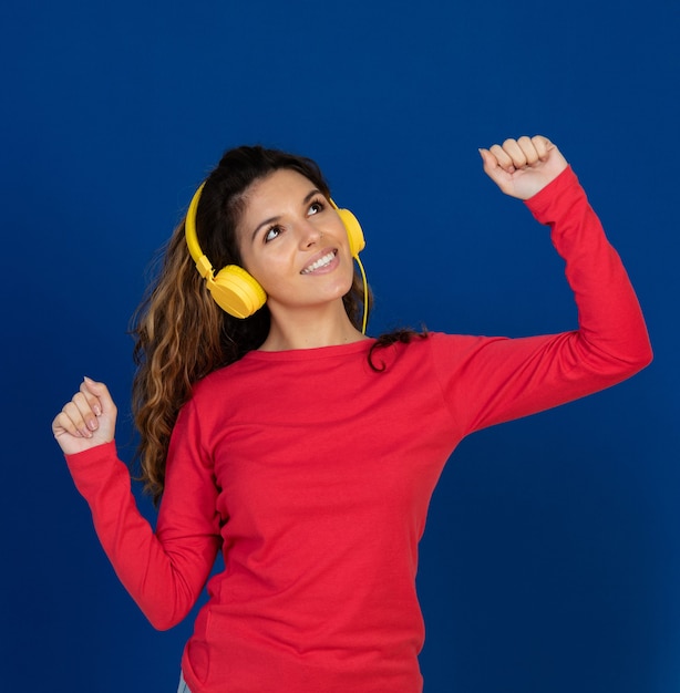 Portrait of beautiful caucasian girl with curly hair and headphones listening music isolated on a white wall